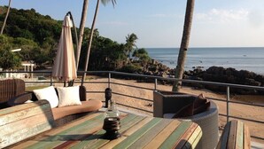 Un espace aménagé avec des meubles en osier, situé au bord de la plage et offrant une vue sur l’océan.