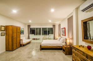 Um quarto com uma cama, um guarda-roupa de madeira, uma mesa de cabeceira com abajur e uma cômoda.