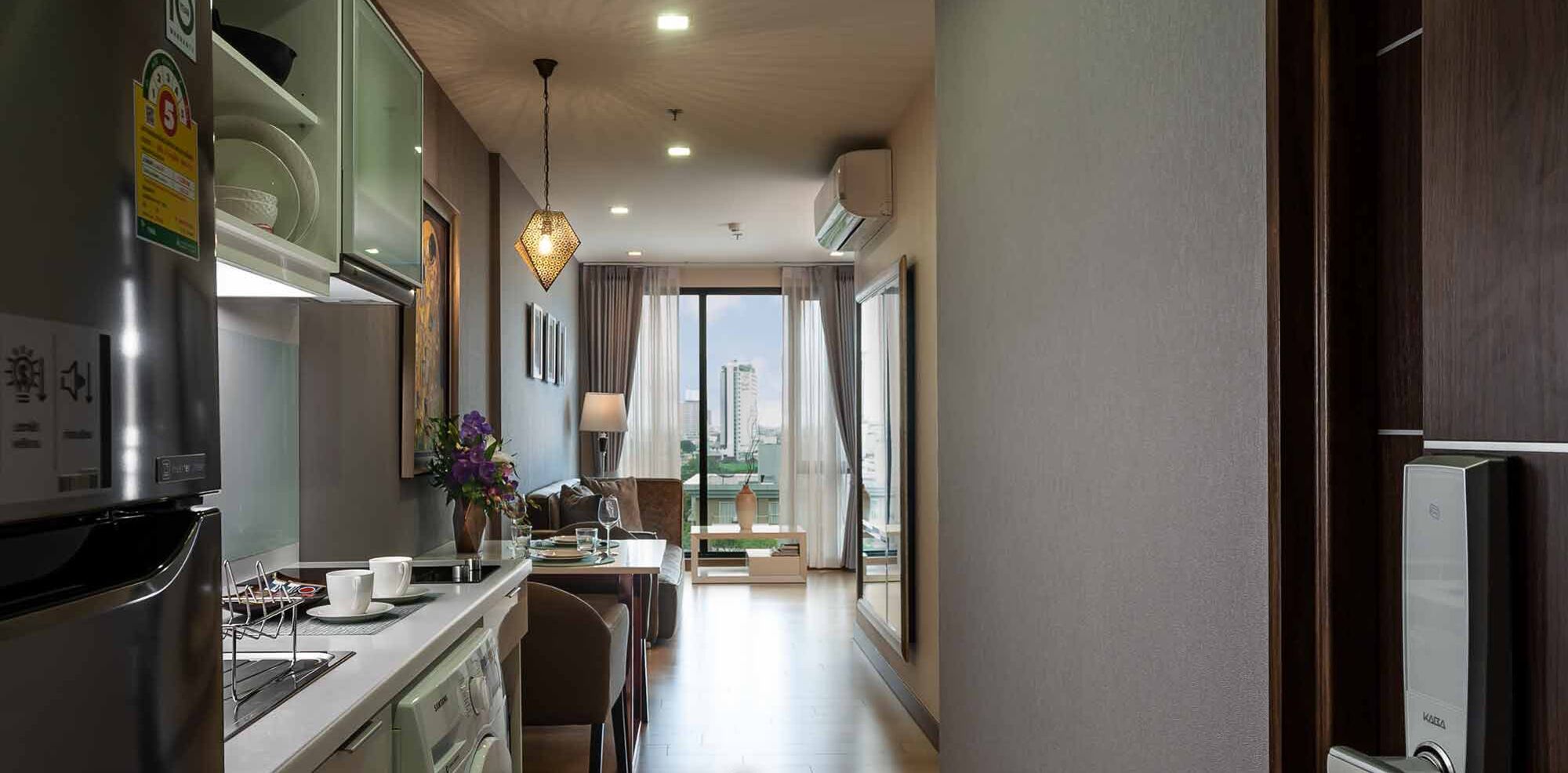 A modern kitchen with a built-in oven, a coffee machine, and a dining area with a view of the city.