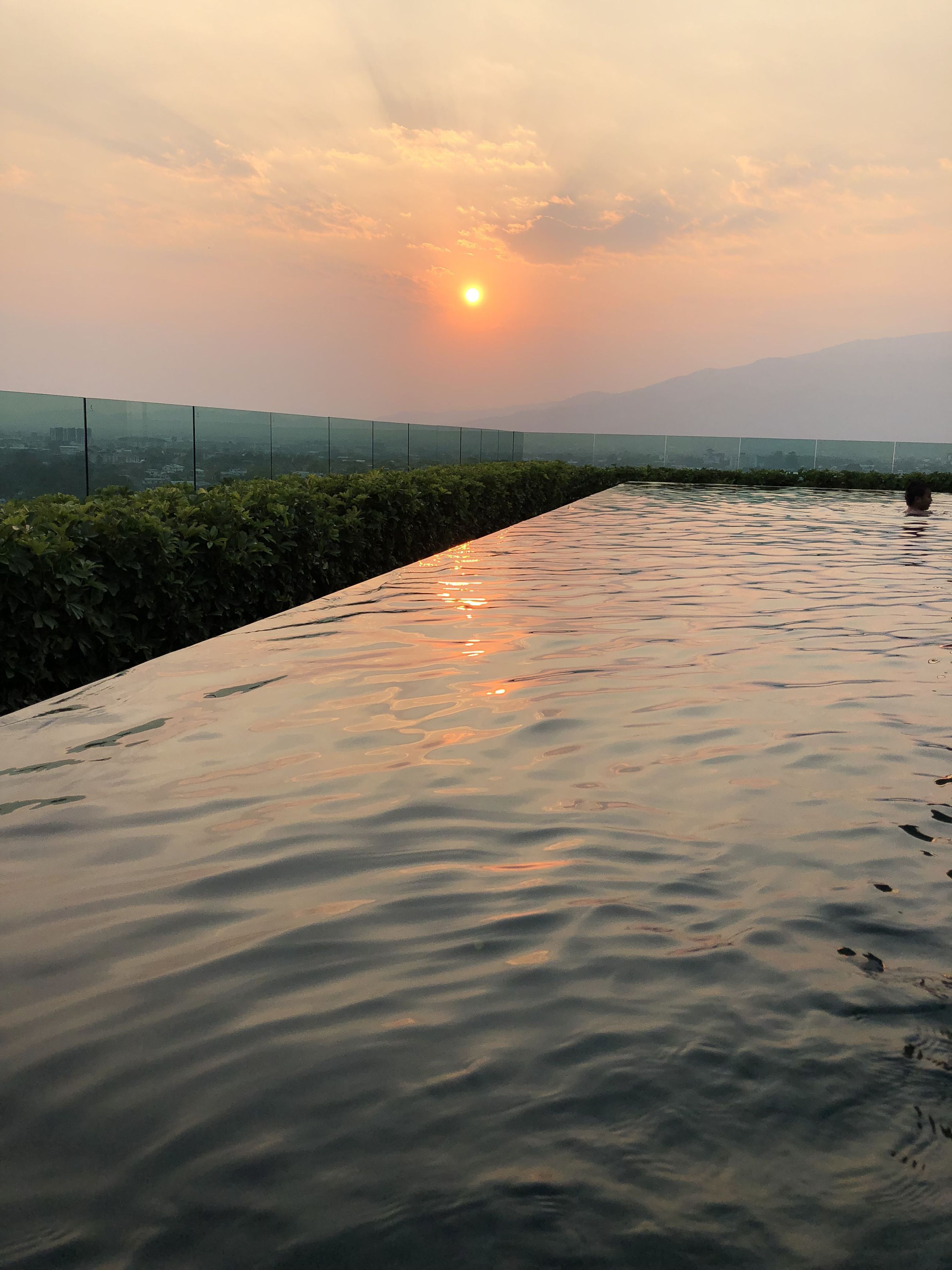 Una piscina en la azotea con vistas a la ciudad y montañas al fondo.