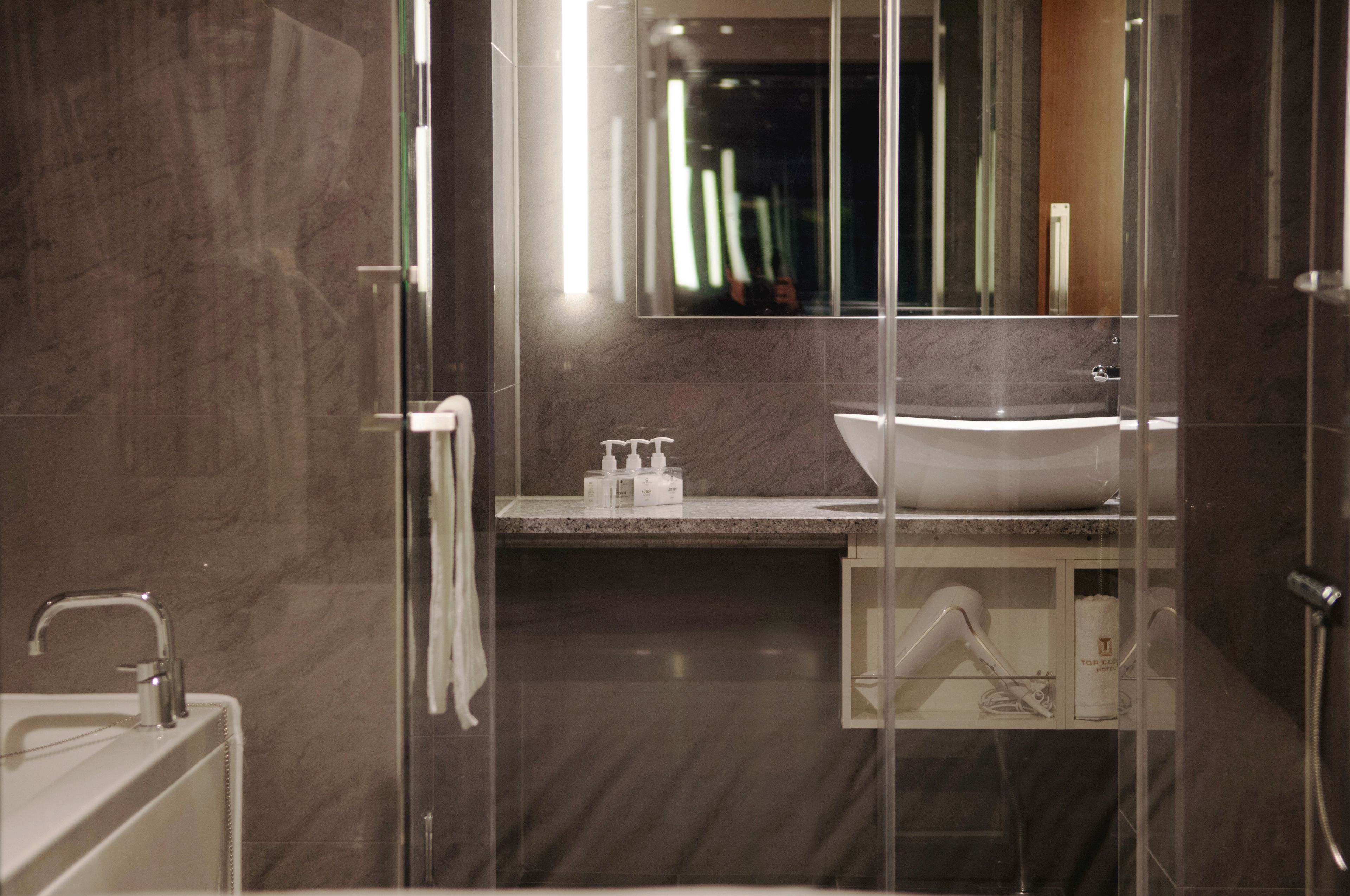 A modern bathroom with a glass-enclosed shower, a white sink, and a marble countertop.