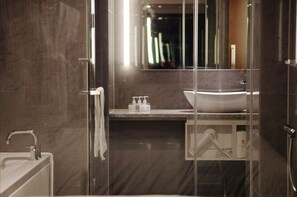 A modern bathroom with a glass-enclosed shower, a white sink, and a marble countertop.