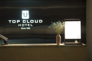 A reception desk with a logo for 'Top Cloud Hotel' and a sign indicating the hotel has been established since 1962.