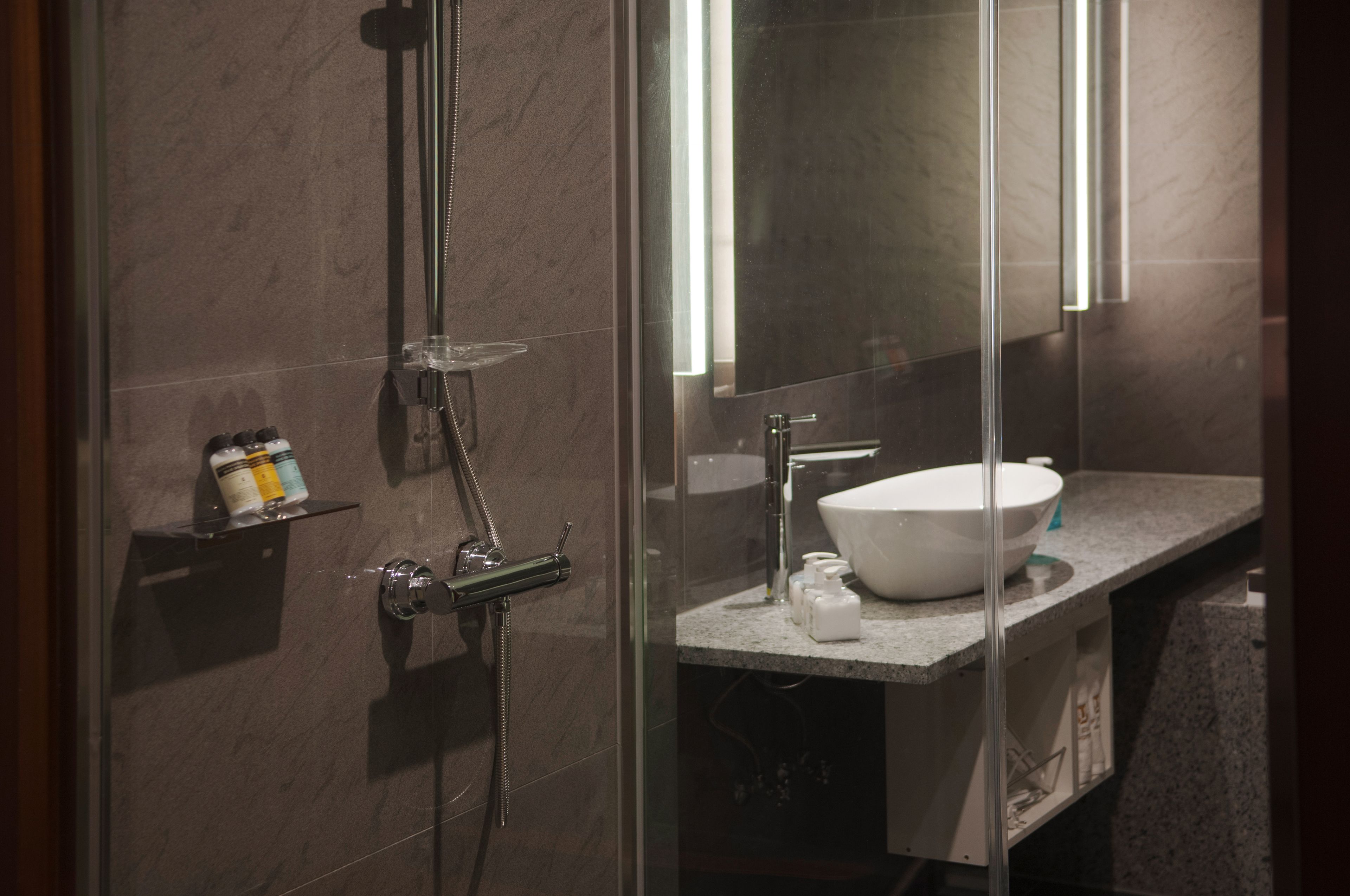 Een moderne badkamer met een douchecabine van glas, een wit wastafelmeubel en een spiegel.