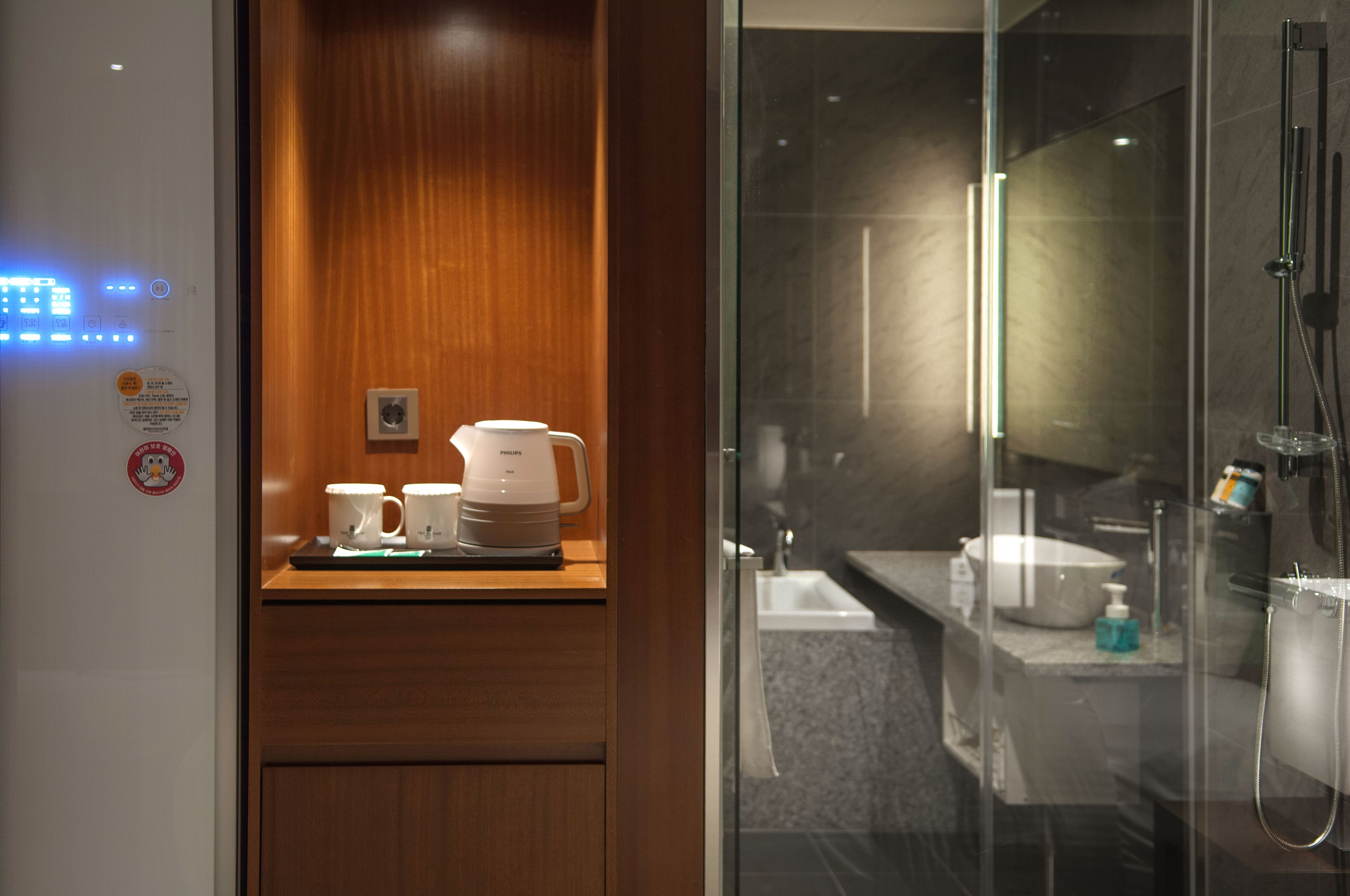 Une salle de bain d’hôtel avec une douche en verre, un lavabo et un coin café équipé de deux tasses et d’une machine à café.