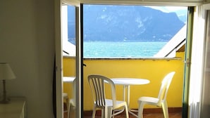 A bedroom with a bed, a table, and two chairs. There is a balcony with a view of the sea and mountains. - Splendor Luxury Penthouse (cir n. 013250CNI00157) (Bellagio)