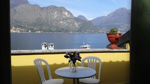 A balcony with a table and chairs, overlooking a lake with mountains in the background. - Splendor Luxury Penthouse (cir n. 013250CNI00157) (Bellagio)
