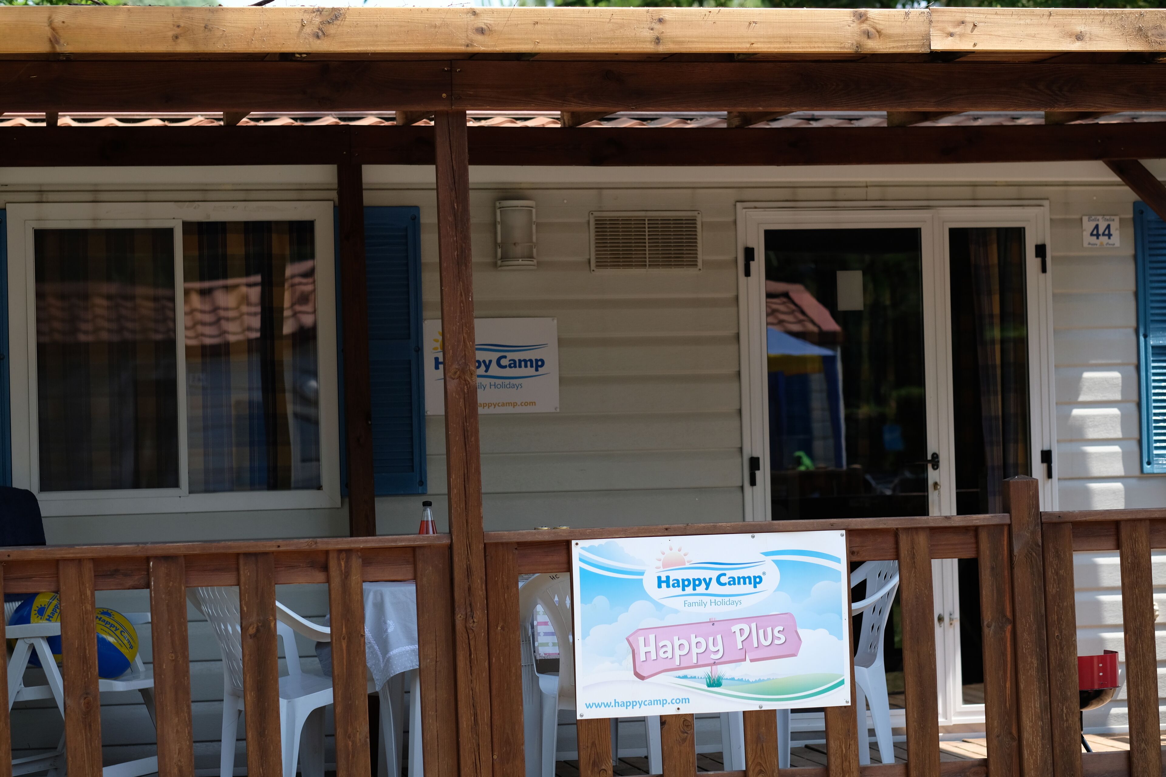 A cabin with a wooden deck, a sign for Happy Camp, and a door labeled 44.
