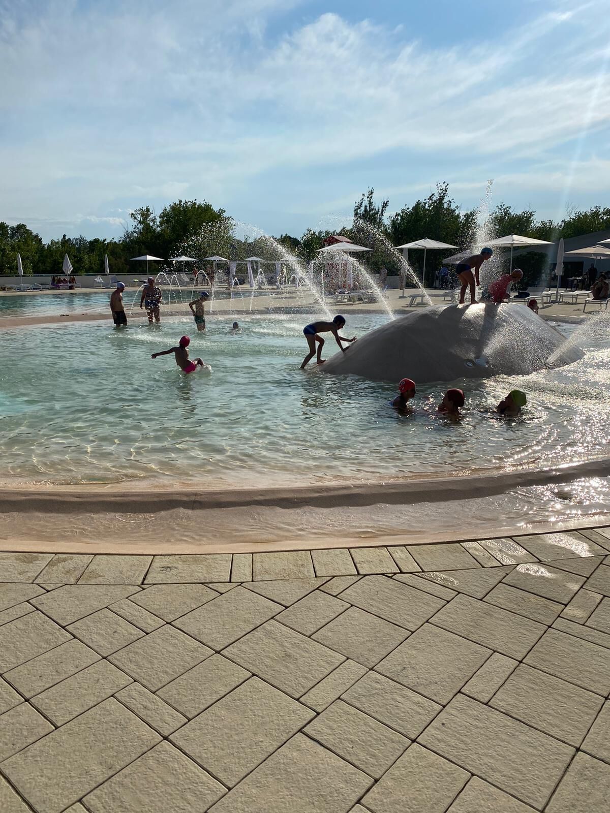 A water play area with multiple fountains and a tiled walkway.