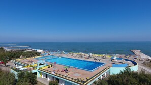 Una piscina al aire libre de temporada, sombrillas, tumbonas