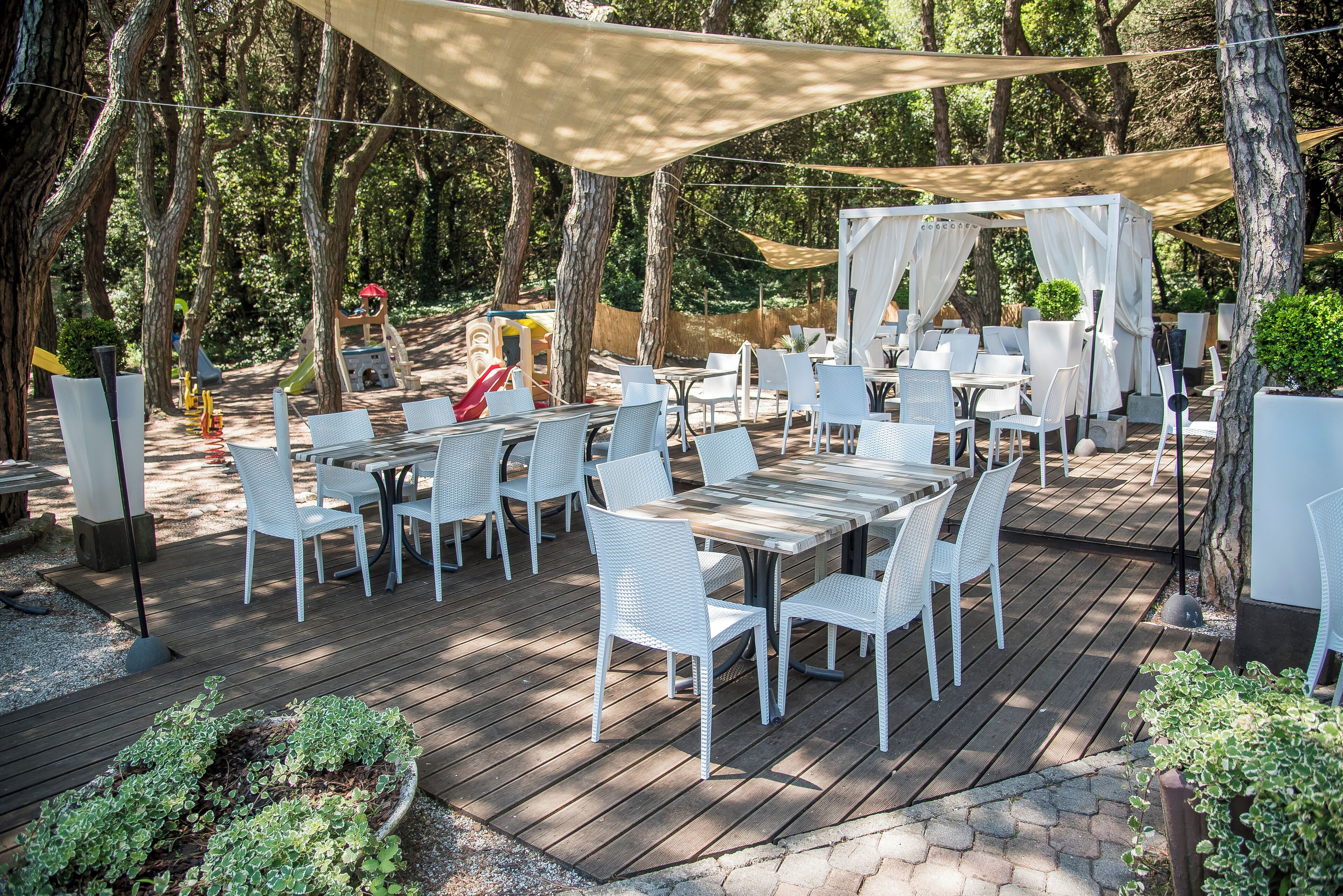 Une terrasse extérieure avec des meubles en osier blanc et une plateforme en bois.