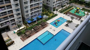 Un immeuble résidentiel doté de nombreux balcons, d’une piscine et d’un espace de jeux pour enfants.