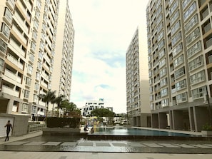 Un complexe d’appartements moderne composé d’immeubles de grande hauteur, d’une cour centrale avec une piscine et d’un espace de jeux pour enfants.