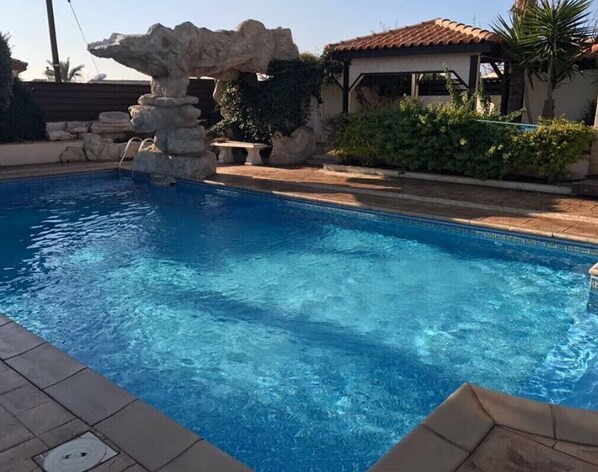 Relax by the serene pool surrounded by a natural stone wall and a scenic rock formation.