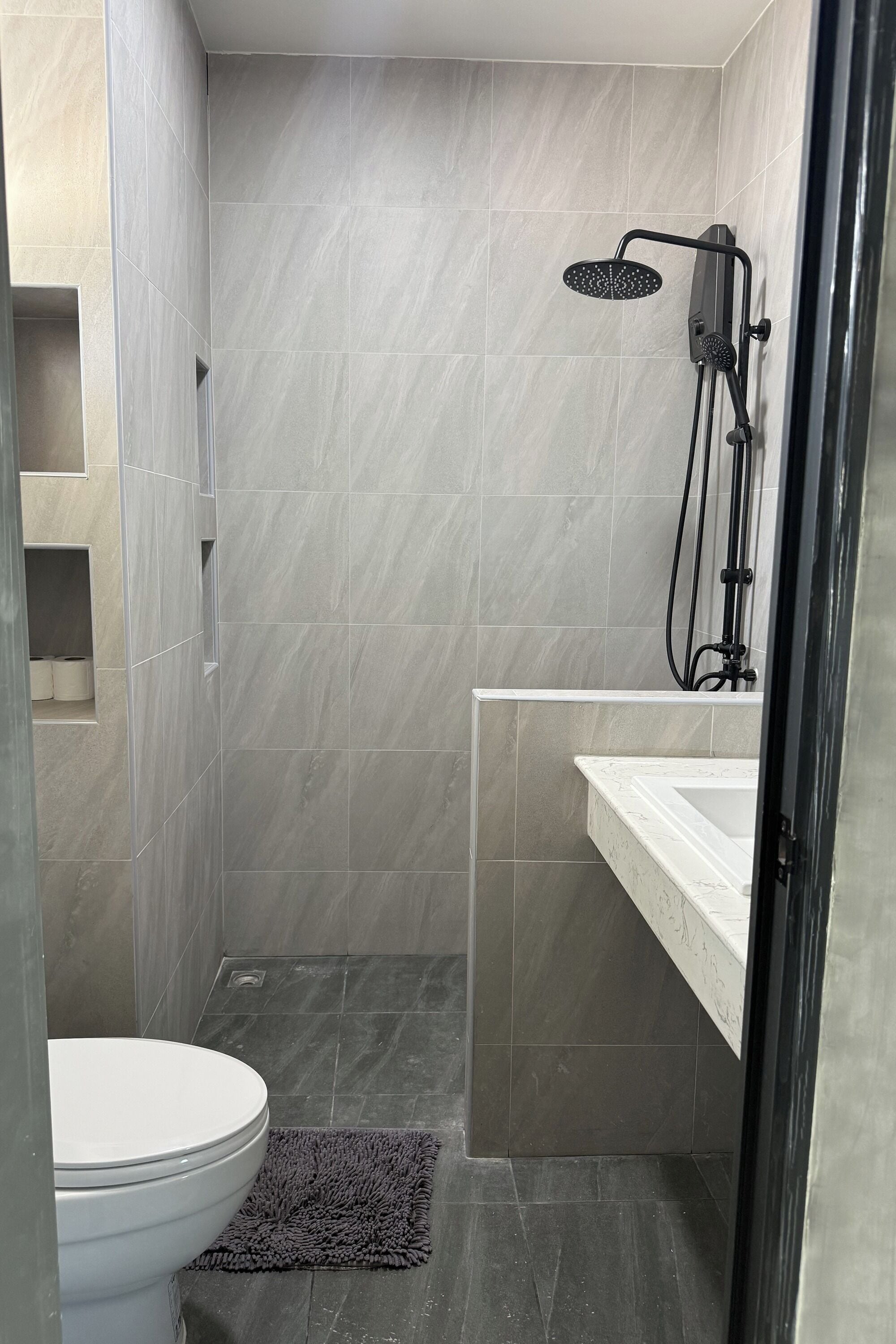 A bathroom with a toilet, a shower, and a sink.