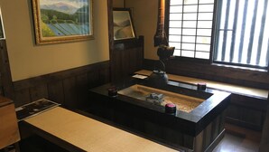 A traditional Japanese room with tatami flooring, a low table with a tea set, and a large window with vertical blinds. - Sujiyu Onsen Daikokuya (Kokonoe)