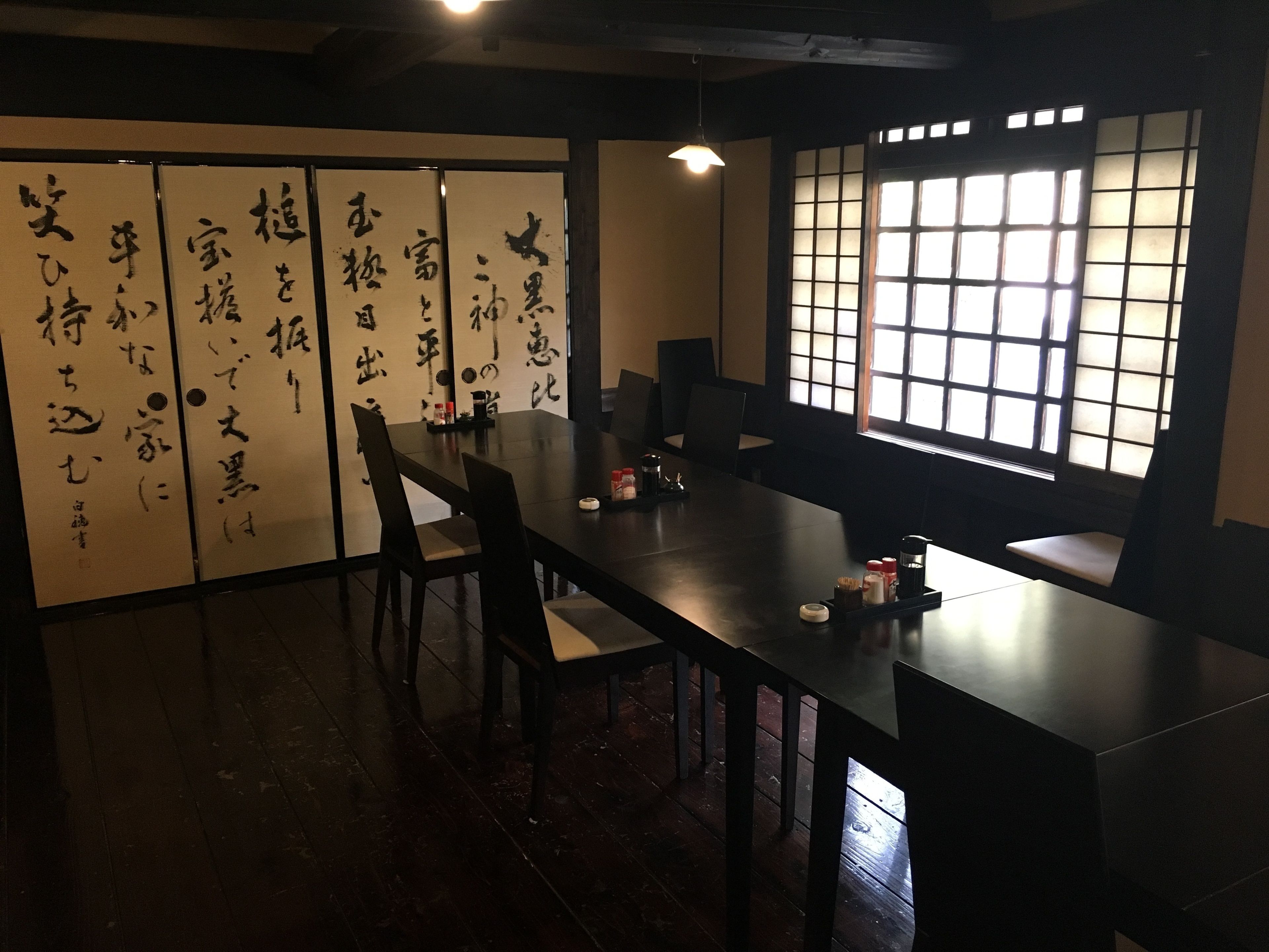 Um quarto japonês tradicional com tatames, uma mesa baixa e portas corrediças com caligrafia.
