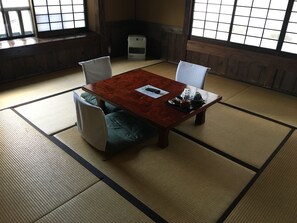 A tatami mat room with a wooden table, two chairs, and a heater. - Sujiyu Onsen Daikokuya (Kokonoe)