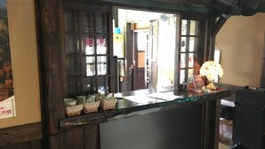 A reception desk with a wooden design, a vase with flowers, and a sign with text. - Sujiyu Onsen Daikokuya (Kokonoe)