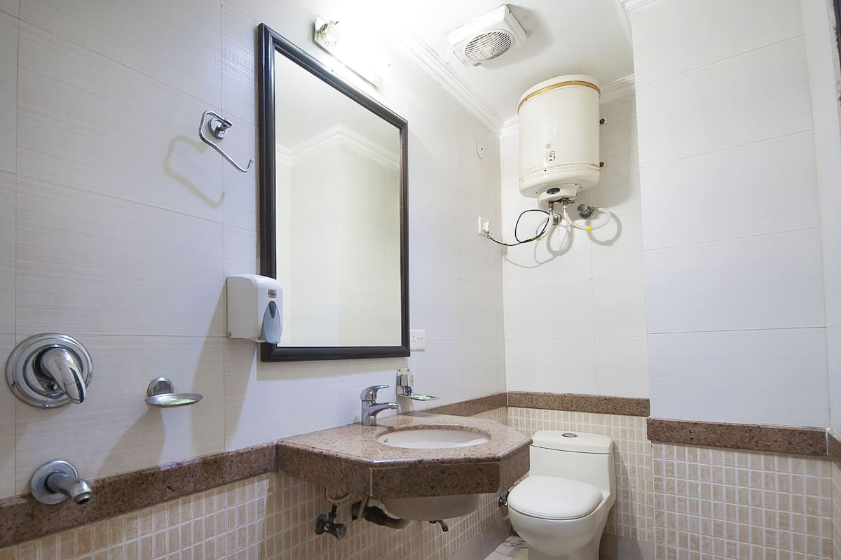 A bathroom with a sink, mirror, toilet, and a water heater mounted on the wall.