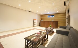 A hotel lobby with a reception desk, seating area, and a map display. - Hotel Dakha International (New Delhi)