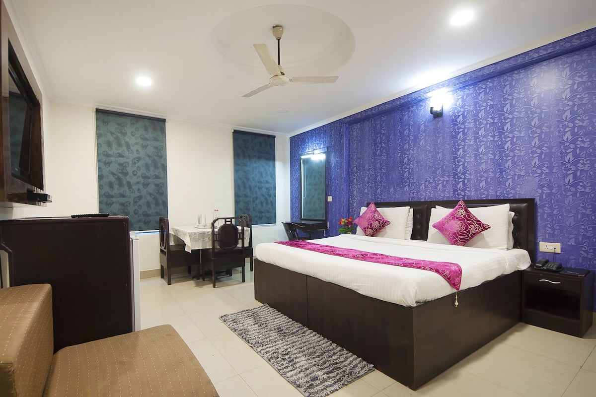 A bedroom with a large bed, a desk, a chair, and a television.