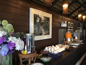 Una mesa de buffet con diversos platos, una cafetera y un cuadro en la pared.