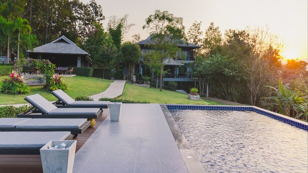 Un resort con piscina, sillas de descanso y un sendero que lleva a un edificio.
