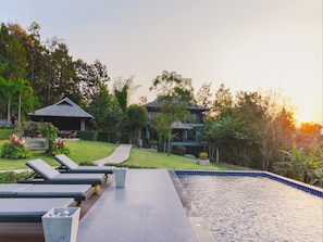 A resort with a swimming pool, lounge chairs, and a pathway leading to a building.