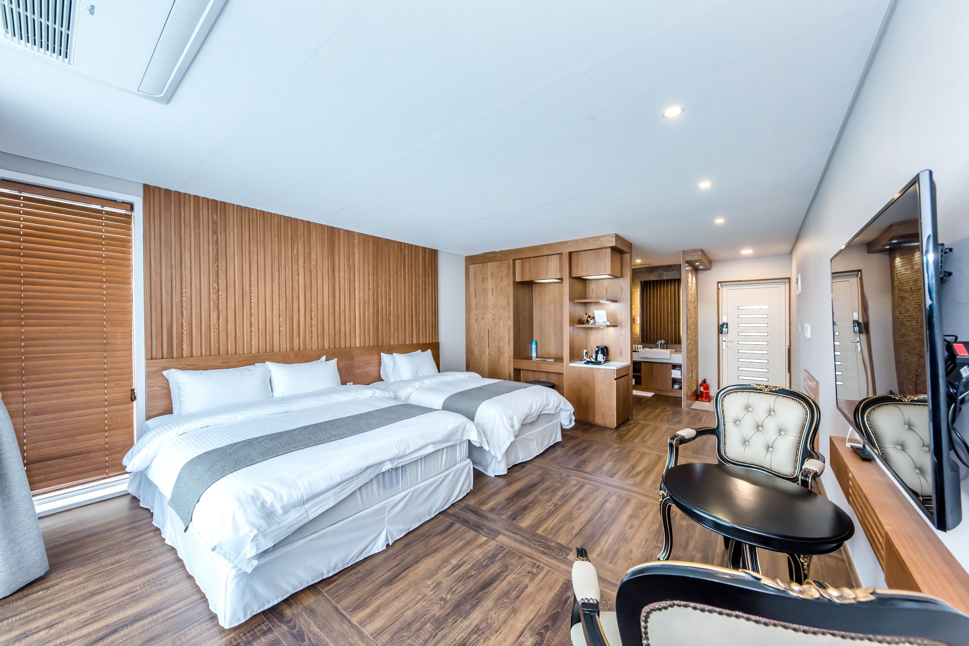 A hotel room with two beds, a vanity with a mirror, a chair, and a TV.