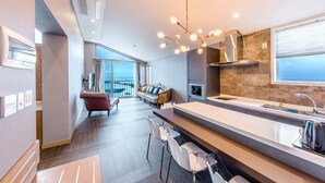 A modern kitchen with a large island, stainless steel appliances, and a view to the outside.