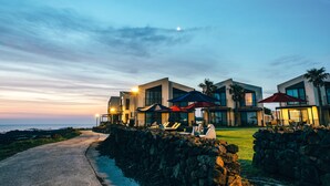 A modern resort with multiple buildings, outdoor seating, and a view of the ocean.