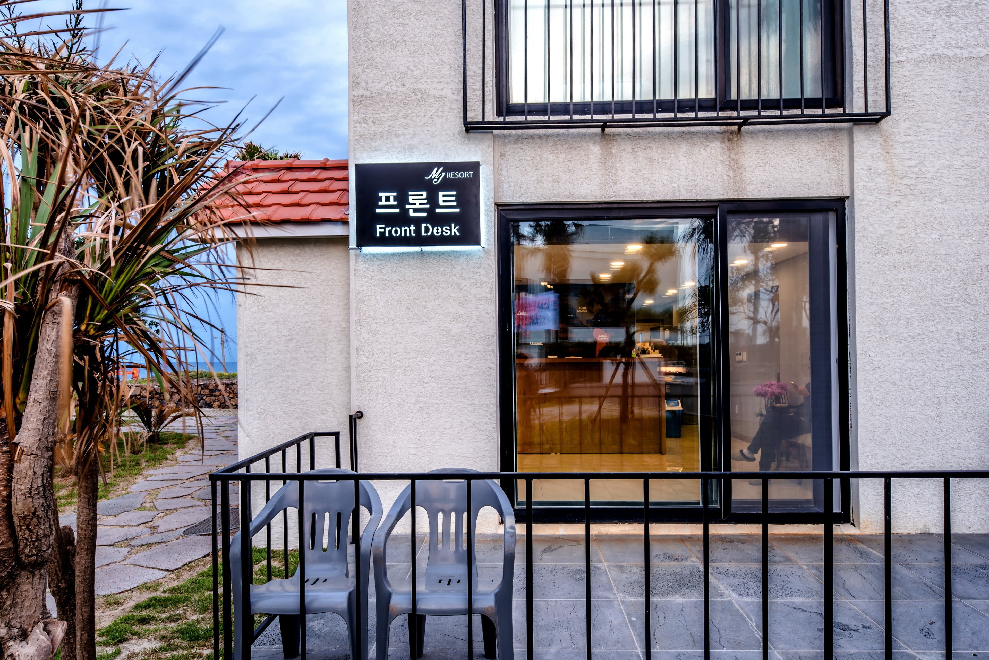 Um edifício com uma placa que diz 'Front Desk' e entrada por porta de vidro.