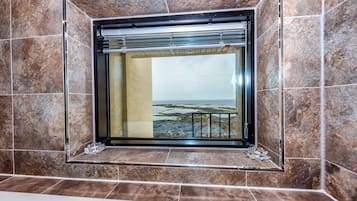 Een badkamer met een groot raam, marmeren tegels en een glazen douchecabine.