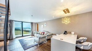 A modern living room with a sofa, a coffee table, and a dining area with chairs.