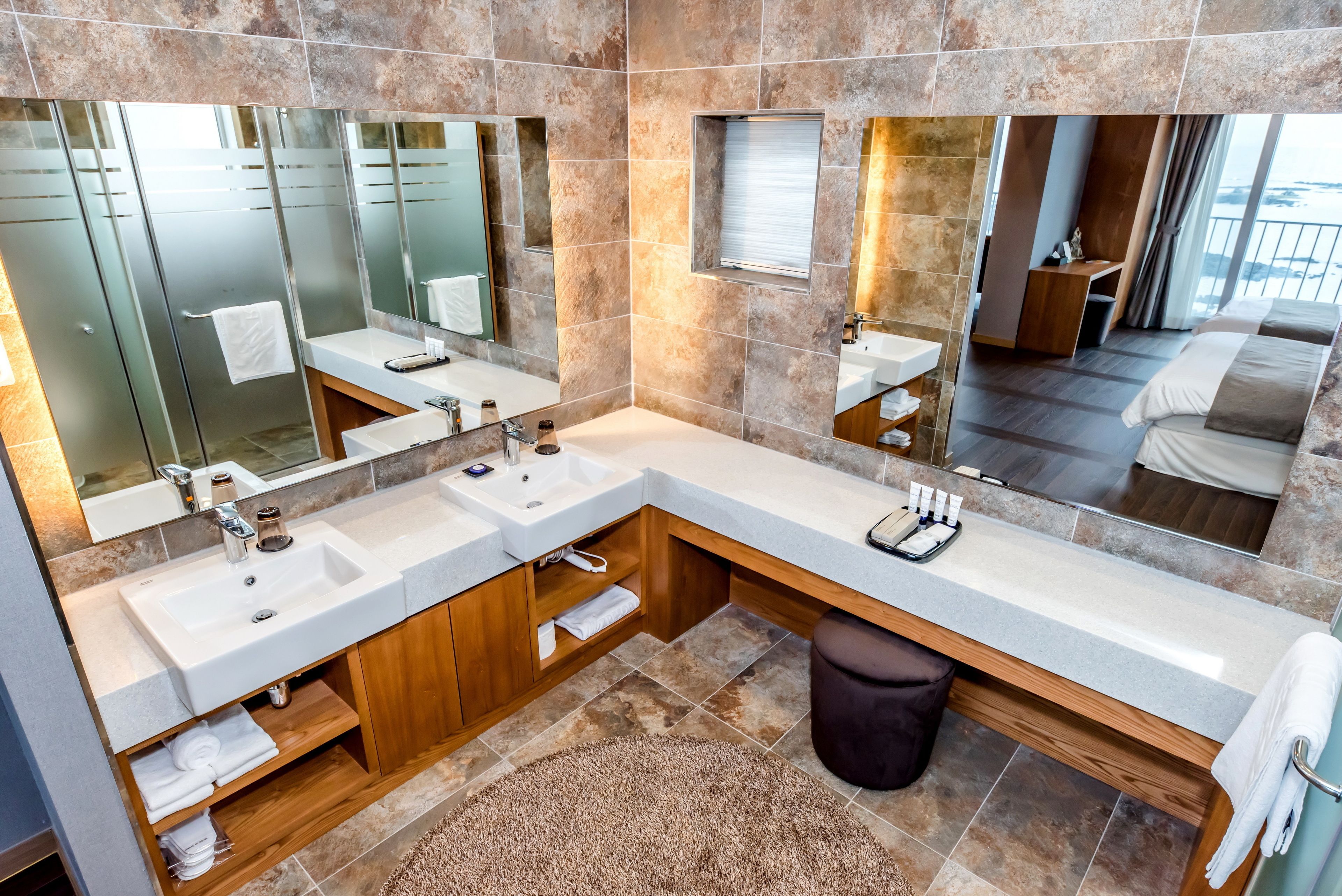 A modern bathroom with two sinks, a large mirror, and a wooden vanity.