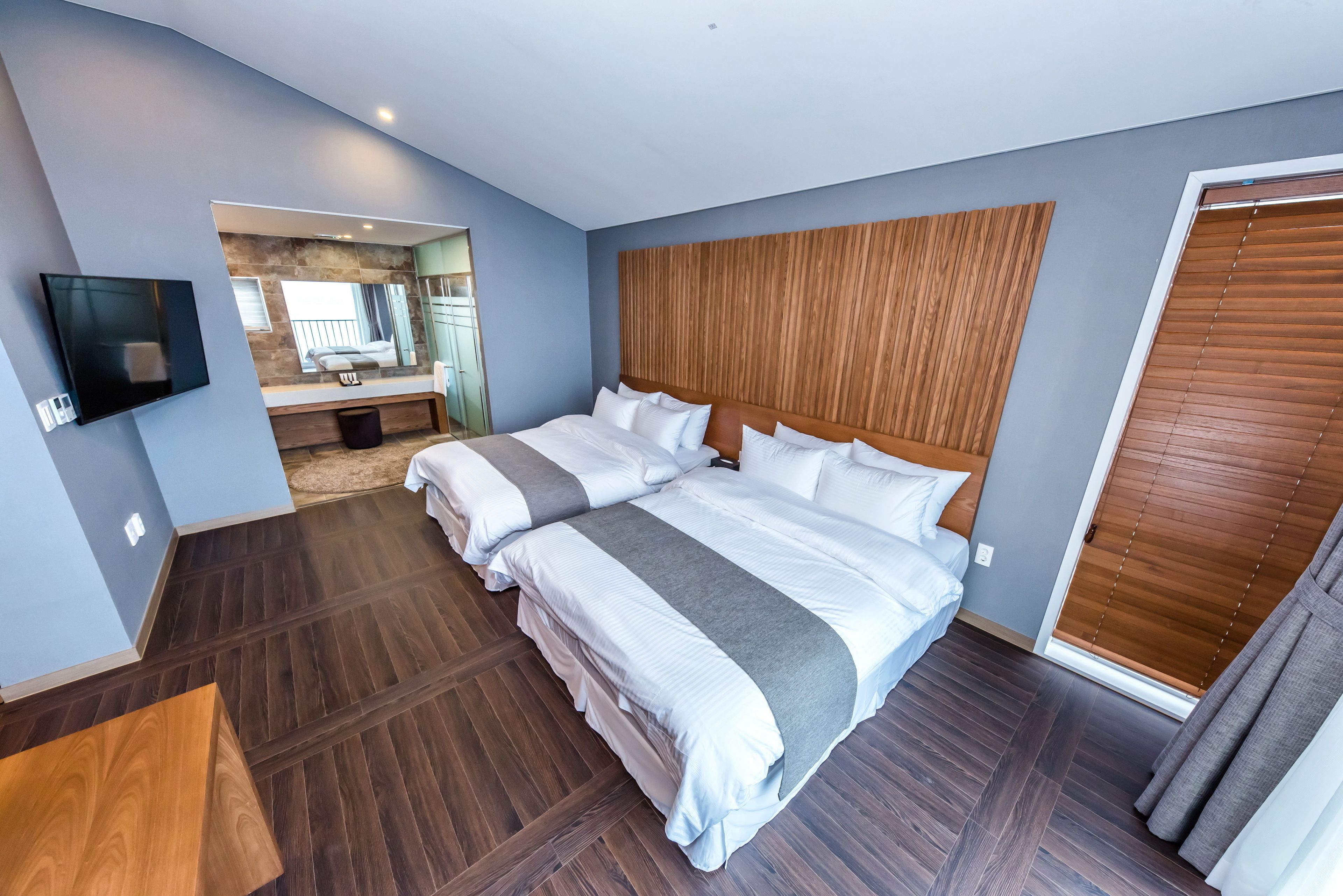 Een moderne hotelkamer met een groot bed, een flatscreen televisie en een houten hoofdeinde.