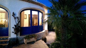 A building with a blue door and windows, a stone pathway, and a palm tree. - Fully Air Conditioned Villa With Heated Pool Set In Large Landscaped Gardens (Alicante)
