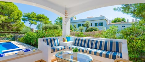 Relax in a serene outdoor space with a comfortable seating area, hot tub, and lush surroundings.