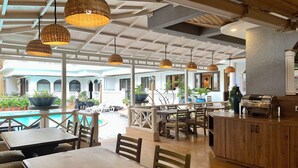 A restaurant with outdoor seating, a pool, and a bar area. - Ziva Suites - A Boutique Hotel (Siolim)