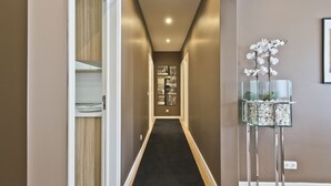 A narrow hallway with a black carpet, wooden cabinets, and a glass display with white flowers. - A modern apartment in Cascais Center (Cascais)