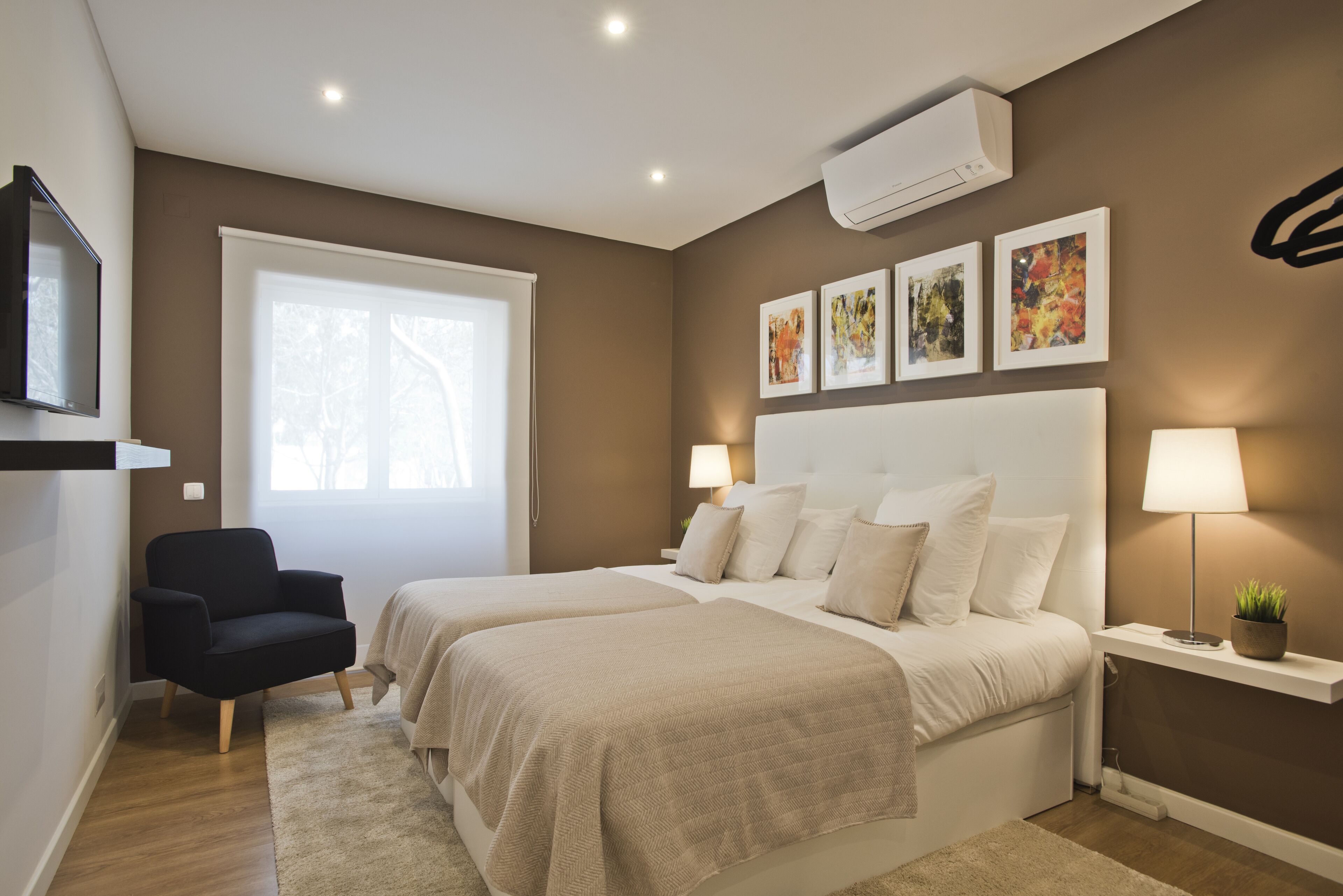 A modern bedroom with two beds, a TV, and artwork on the wall.