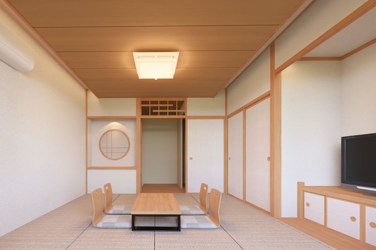 Una habitación tradicional japonesa con suelo de tatami, techo de madera bajo, una puerta corredera y un televisor sobre un soporte de madera.