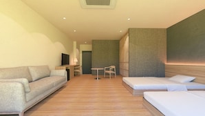 A modern hotel room with a sofa, a bed, a TV, a desk, and a chair. - Okutamaji (Ome)