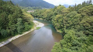 Un río serpenteando por un valle boscoso, con un edificio en la orilla izquierda.