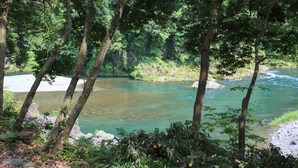 Un paisaje natural con un río, árboles y terreno rocoso.