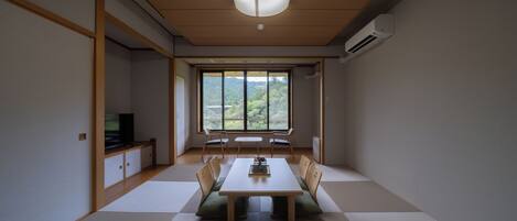 A minimalist Japanese-style room with tatami flooring, a low table, and a television on a cabinet.