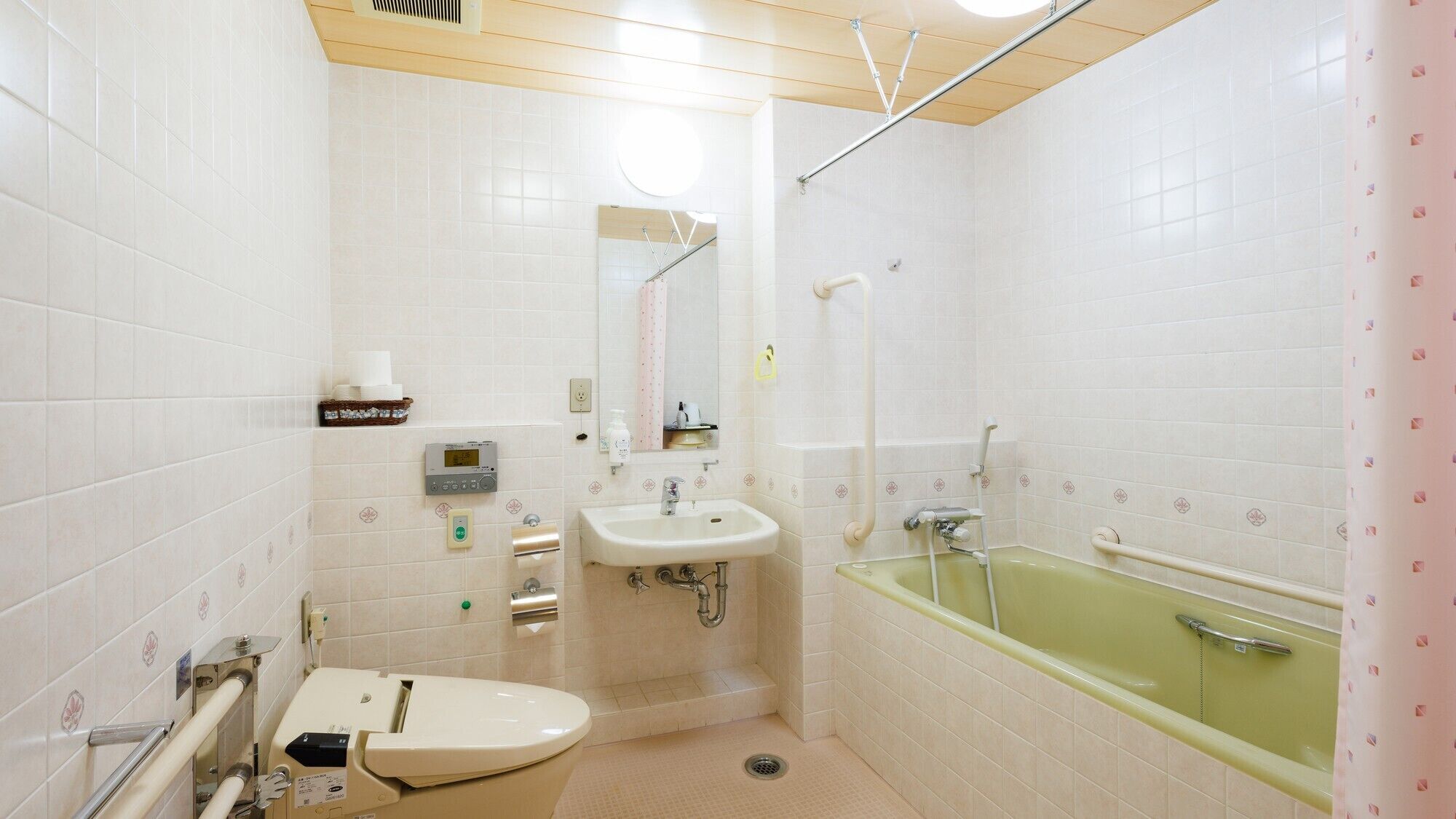 A bathroom with a toilet, sink, and bathtub, equipped with a hand dryer and a towel rack.