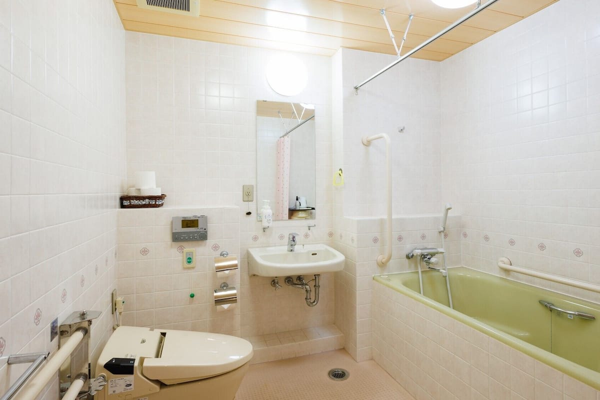 Baño con inodoro, lavabo y bañera, equipado con secamanos y toallero.