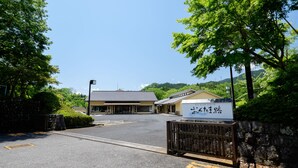 A parking lot with a building in the background, surrounded by greenery. - Okutamaji (Ome)